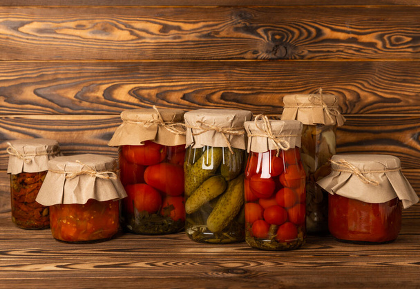 Jars of pickled vegetables. Marinated food.Assortment of homemade jars with a variety of marinated and pickled vegetables on a wooden table. Housekeeping and harvesting. - Zdjęcie, obraz