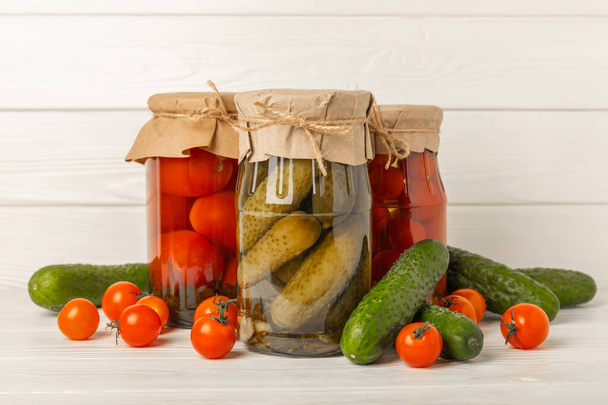 酢漬け野菜の瓶。漬物:キュウリとトマトの素朴な木製の背景に。漬物・缶詰. - 写真・画像