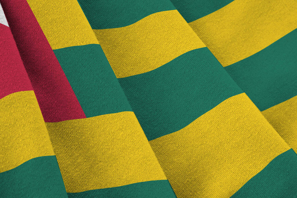 Bandiera Togo con grandi pieghe sventolando da vicino sotto la luce dello studio all'interno. I simboli ufficiali e i colori nel banner in tessuto - Foto, immagini
