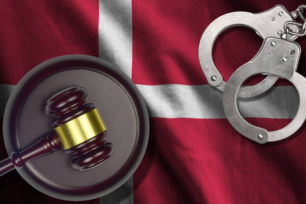 Denmark flag with judge mallet and handcuffs in dark room. Concept of criminal and punishment, background for guilty topics - Photo, Image