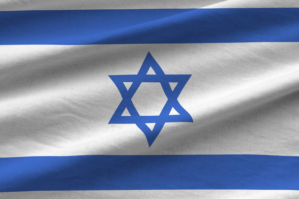 Israel-Flagge mit großen Falten, die aus nächster Nähe unter dem Studiolicht im Innenraum weht. Die offiziellen Symbole und Farben in Stoffbanner - Foto, Bild