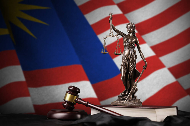 Maleisië vlag met standbeeld van dame gerechtigheid, grondwet en rechter hamer op zwarte draperie. Begrip oordeel en straf - Foto, afbeelding