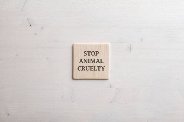 Telha de madeira com um sinal de crueldade Stop animal sobre ele colocado simples fundo de madeira simples com espaço de cópia. - Foto, Imagem
