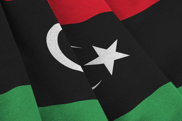 Σημαία Λιβύης με μεγάλες πτυχές να κυματίζουν κοντά κάτω από το φως του στούντιο σε εσωτερικούς χώρους. Τα επίσημα σύμβολα και τα χρώματα σε banner ύφασμα - Φωτογραφία, εικόνα
