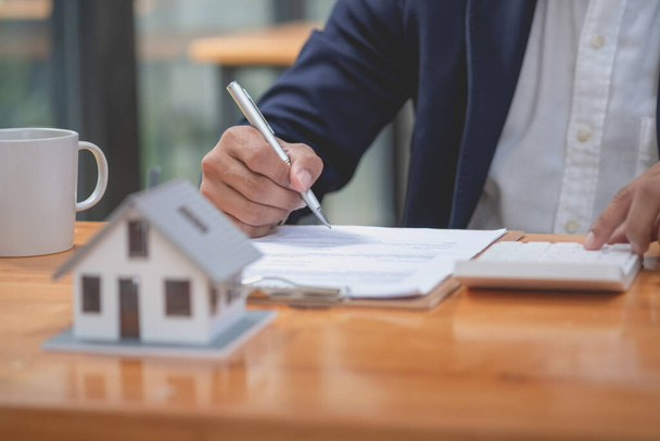 Accountant, businessman, real estate agent, businessman handing model house to customers along with house interest calculation documents for customers to sign. - Foto, Imagem