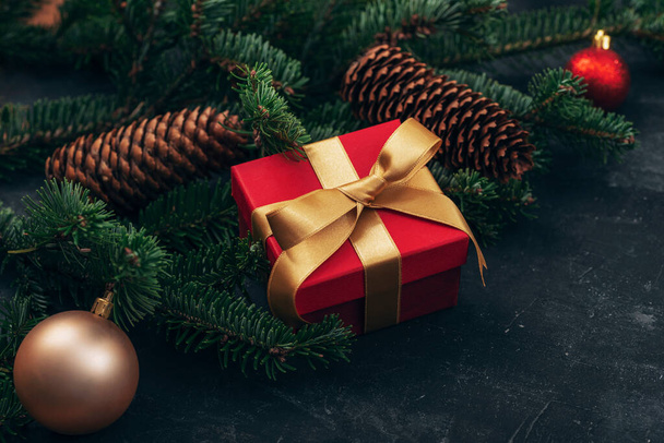 Kırmızı hediye kutusu, Noel mücevherleri, köknar ağacı ve siyah arka planda koniler. Kış tatili konsepti. Üst görünüm. - Fotoğraf, Görsel