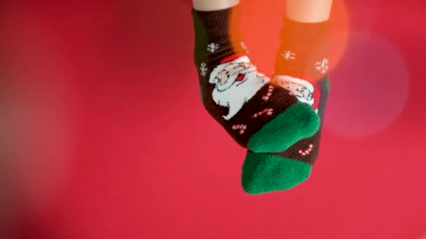Жіночі ноги на різдвяних шкарпетках з Санта Клаусом на червоному фоні, ноги танцюють. - Кадри, відео