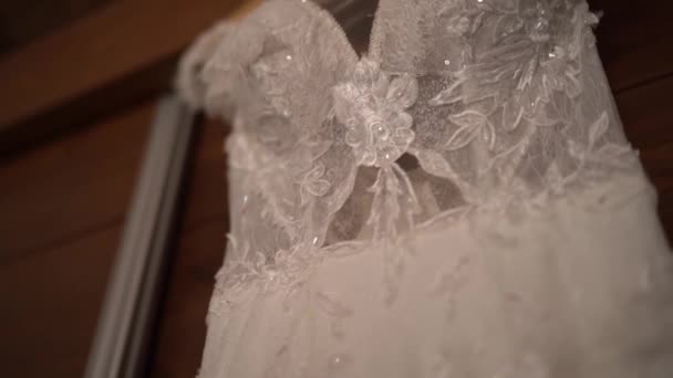 Robe de mariée en dentelle avec strass et fleurs brodées accrochées à un cintre. Des images FullHD de haute qualité - Séquence, vidéo