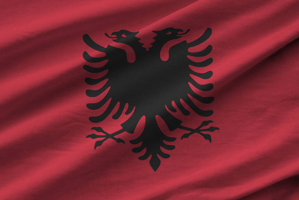 Прапор Албанії з великими складками, що махають під освітленням студії. Офіційні символи та кольори на тканині. - Фото, зображення