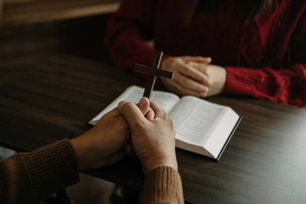 man Hands holding cross at table with woman, reading bible book  - Foto, immagini