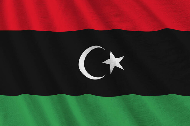 Bandera de Libia con grandes pliegues ondeando de cerca bajo la luz del estudio en el interior. Los símbolos oficiales y los colores en banner de tela - Foto, imagen