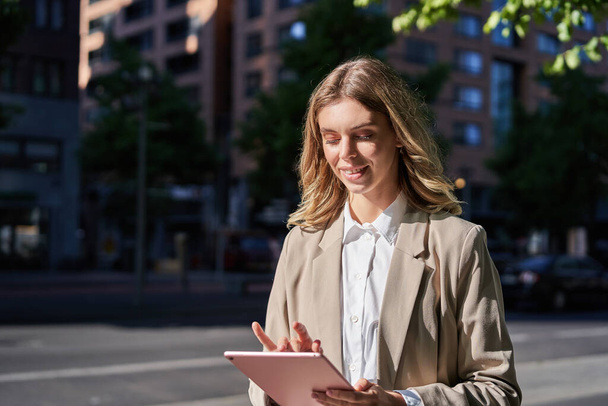 Retrato de mulher corporativa usando seu tablet digital, trabalhando e andando na rua, indo ao escritório, multitarefa. - Foto, Imagem