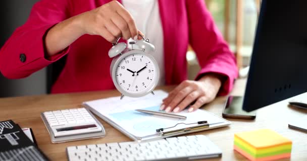 Bizneswoman pokazuje czas na budzik na pulpicie zbliżenie 4k film slow motion. Koncepcja zarządzania czasem - Materiał filmowy, wideo