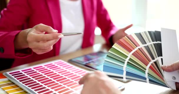 Σχεδιαστής βοηθώντας τον πελάτη να επιλέξει χρώμα χρησιμοποιώντας κατάλογο closeup 4k ταινία αργή κίνηση. Έννοια εσωτερικού σχεδιασμού - Πλάνα, βίντεο