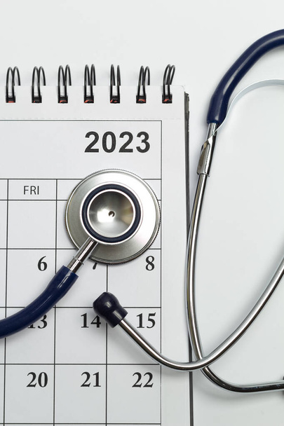 Page with calendar dates for 2023 and stethoscope as medicine concept. - Fotoğraf, Görsel