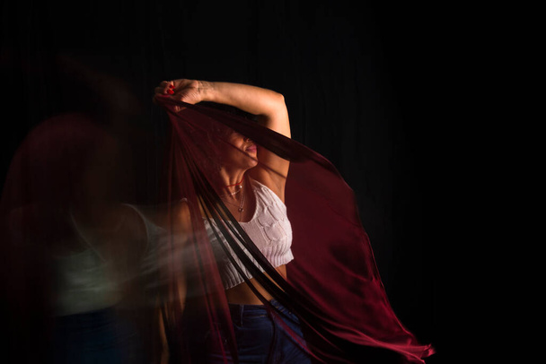 Γυναίκα κινείται ένα κόκκινο πανί πάνω από το κεφάλι της σε μαύρο φόντο. Ευτυχισμένη γυναίκα. Σαλβαδόρ, Βραζιλία. - Φωτογραφία, εικόνα