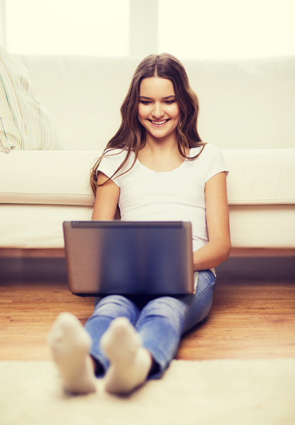 Улыбающаяся девочка-подросток с ноутбуком дома
 - Фото, изображение