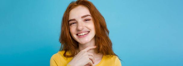 Retrato de pelirroja feliz chica de pelo rojo con pecas sonriendo mirando a la cámara. Fondo azul pastel. Copiar espacio. - Foto, imagen