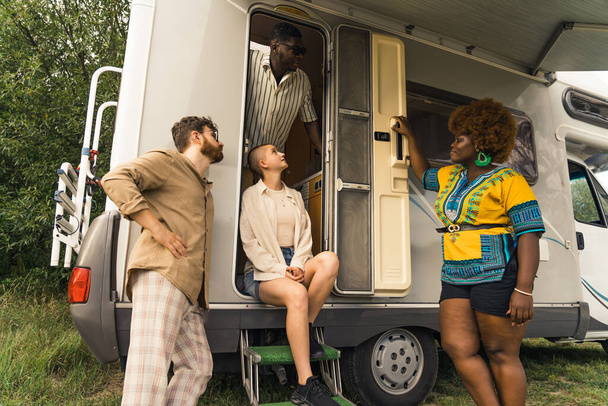 Grupo relajado de amigos multiculturales y multiétnicos de pie frente a su caravana y mirando a su nuevo lado de acampada. Un disparo al aire libre. Foto de alta calidad - Foto, imagen