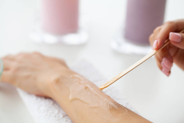 Meister macht Epilation der Hände mit Hilfe von Zuckerpaste heißes Wachs in Salon Schönheit. - Foto, Bild