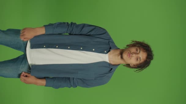 Vertical Footage. Young Motivated Multicultural Curly Freelancer Student Man in Denim Shirt Feeling Disappointed and Making Thumbs Down Gesture Straight to the Camera on Green Screen Background. - Footage, Video