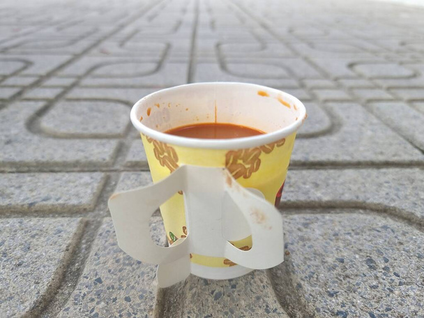 Ζεστός καφές ή ζεστό τσάι σε ένα φλιτζάνι χαρτί τοποθετείται στο πάτωμα. - Φωτογραφία, εικόνα