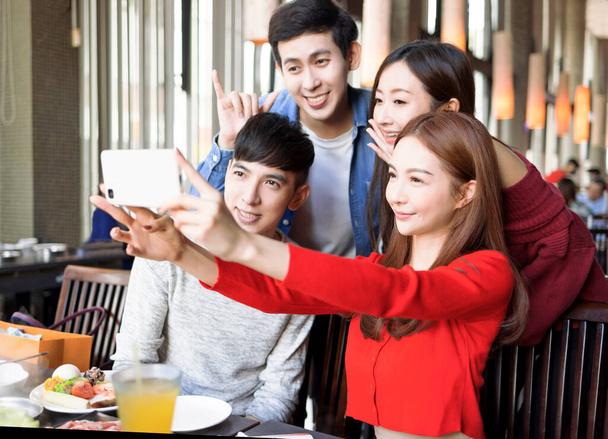 Happy young friends are taking selfie in restaurant - Photo, Image