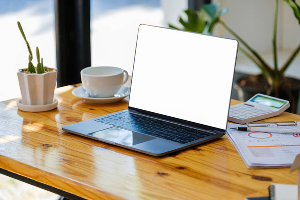 Ein Computer mit weißem Bildschirm auf einem Holztisch kann Textnachrichten oder Bilder auf einem leeren Bildschirm transportieren - Foto, Bild