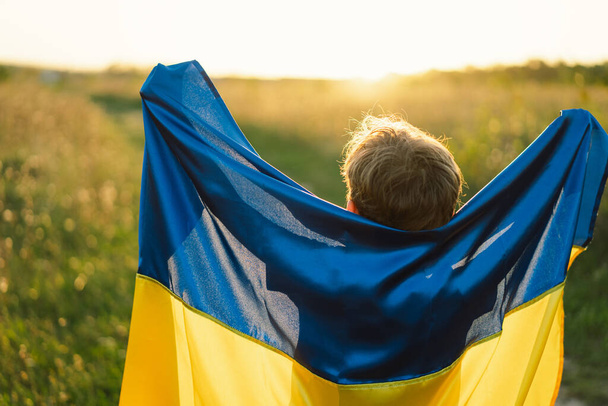 Dia da Independência da Ucrânia. Menino em camiseta branca com bandeira amarela e azul da Ucrânia no campo. Bandeira da Ucrânia. Dia da Constituição. Fique com a Ucrânia e Save - Foto, Imagem