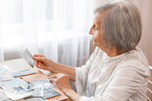 Senior mulher está olhando suas próprias fotos antigas em casa. Mulher idosa tem um sorriso ao lembrar o quão jovem e beatiful ela era. Foco seletivo. Foto tirada em 1953 - Foto, Imagem