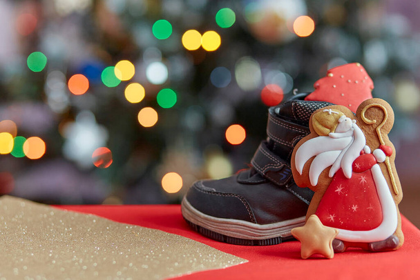 Boots filled of treats. Saint Nicholas cookies on bokeh background. Traditional holiday in Europe. Copy space - Photo, Image