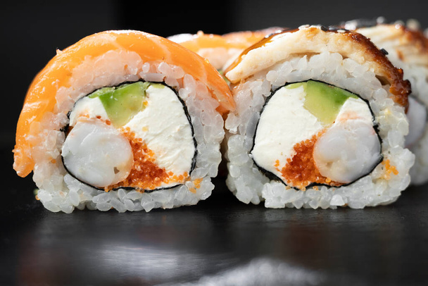 Philadelphia roll sushi with salmon, prawn, avocado, cream cheese over dark stone background. Sushi menu. Japanese food. - Фото, зображення
