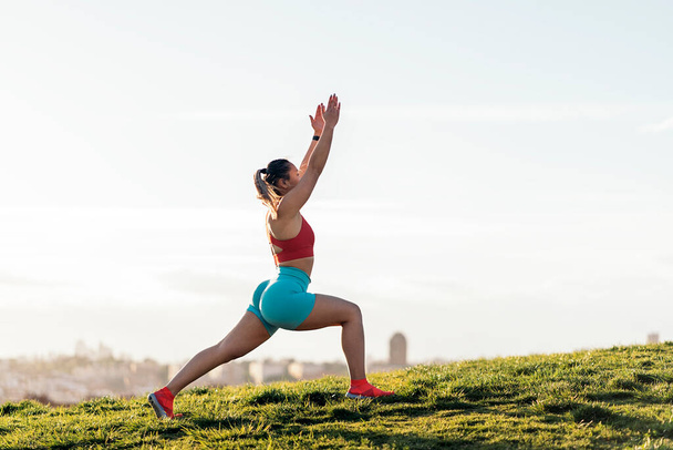 Tanımlanamayan bir kadın spor kıyafetleri içinde parkta yoga pozu veriyor ve antrenman yapıyor. Güçlü ve esnek.. - Fotoğraf, Görsel
