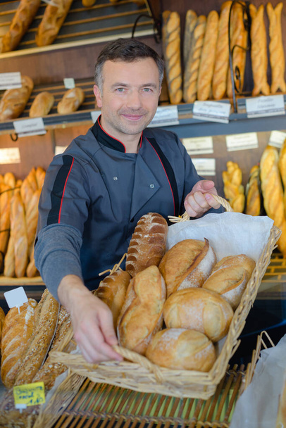 bakery shopkeeper is proud of his bread production - Foto, afbeelding