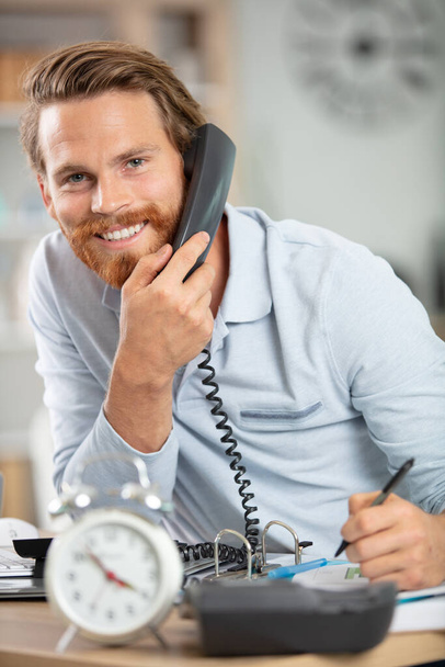 cheerful man in office answering the phone - Fotó, kép