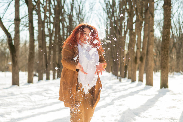 Läski valkoihoinen nainen pelaa lumipalloja puistossa - Valokuva, kuva