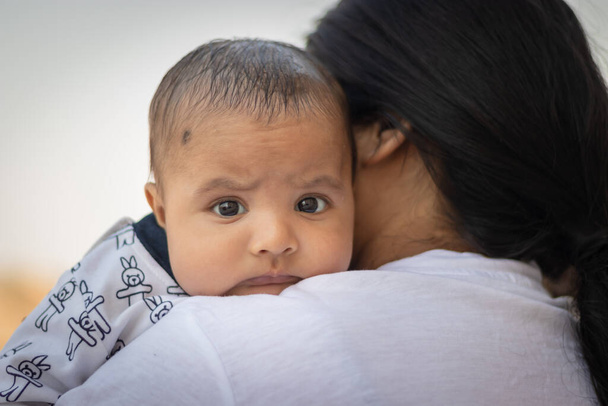 słodkie niemowlę wyraz twarzy spoczywa na ramieniu matki z płaskim kątem - Zdjęcie, obraz
