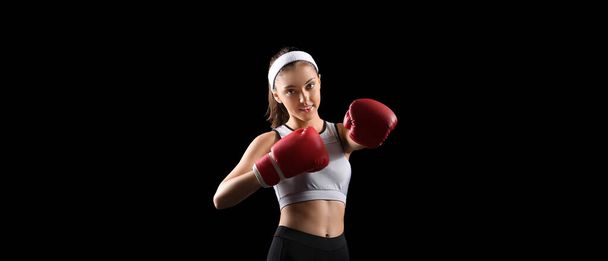 Desportivo jovem mulher em luvas de boxe no fundo preto - Foto, Imagem