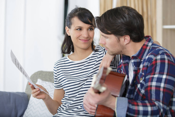 couple in love playing acoustic guitar at home - Photo, Image