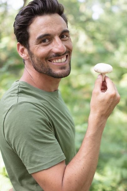 young man picking mushrooms in forest - Φωτογραφία, εικόνα