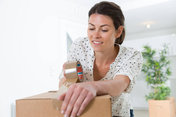 woman closing boxes to move to her new house - Foto, imagen