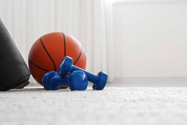 Dumbbells and ball on floor in light room - Photo, image