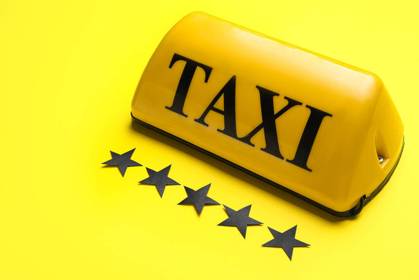 Ταξί πινακίδα οροφής και χάρτινα αστέρια σε κίτρινο φόντο - Φωτογραφία, εικόνα