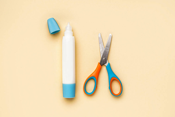 Tube of glue and scissors on color background - Foto, Imagen