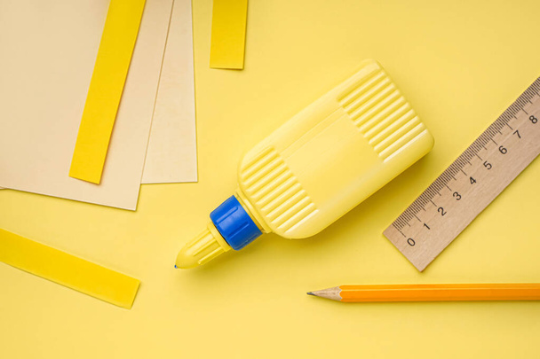 Lahvička lepidla, tužky a pravítka na žlutém pozadí - Fotografie, Obrázek