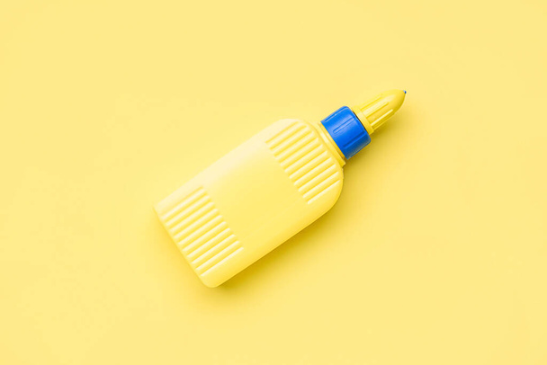 Бутылка клея на желтом фоне - Фото, изображение