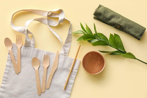 Sacola de tecido, utensílios de mesa Eco e ramo de planta no fundo amarelo - Foto, Imagem