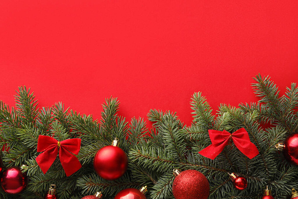 Beautiful composition with fir branches and Christmas decorations on red background - Photo, Image