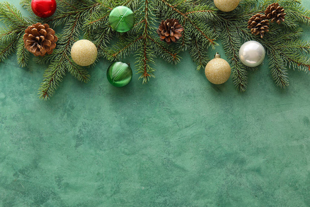 Fir takken met kerstballen en dennenappels op groene achtergrond - Foto, afbeelding