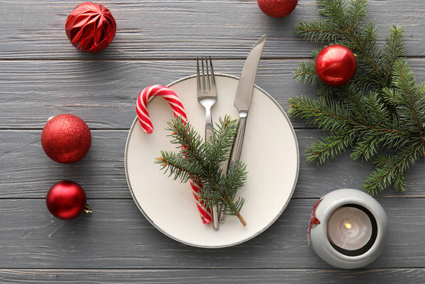 Apparecchiatura della tavola con palline di Natale, bastoncini di zucchero e rami di abete su sfondo grigio in legno - Foto, immagini